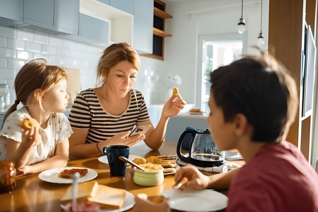 A photo of a messy kitchen counter with half-eaten snacks, coffee cups, and kids' lunchboxes - the reality of busy mom life